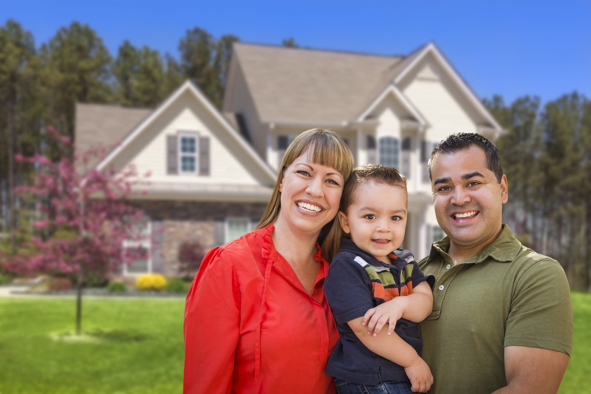 Happy Mixed Race Young Family In Front Of Beautiful House.