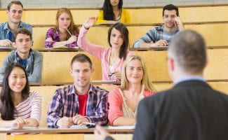 Rear View Of An Elegant Teacher With Students Sitting At The College Lecture Hall