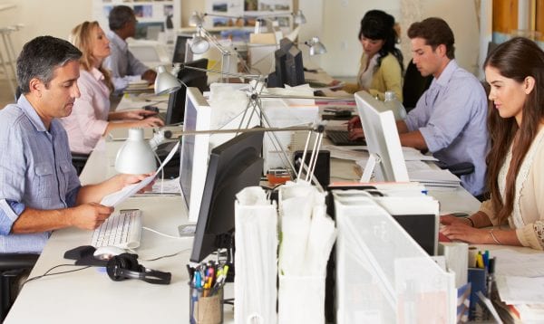 Team Working At Desks In Busy Office